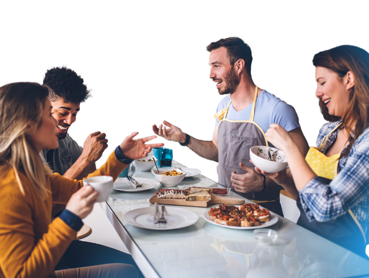 Men and women are gathered around a table, engaging in conversation while eating, with a blue background.